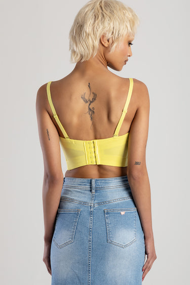 back view of a person wearing a yellow corset top with adjustable straps and a blue denim skirt