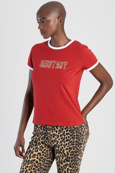 woman model wearing a red short sleeve top with white trim and rhinestone lettering on the chest, paired with leopard print
