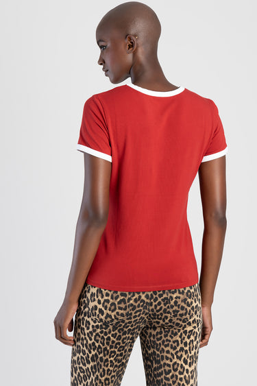 red short sleeve top with white trim at the neckline and cuffs on a model, leopard print pants visible from the back