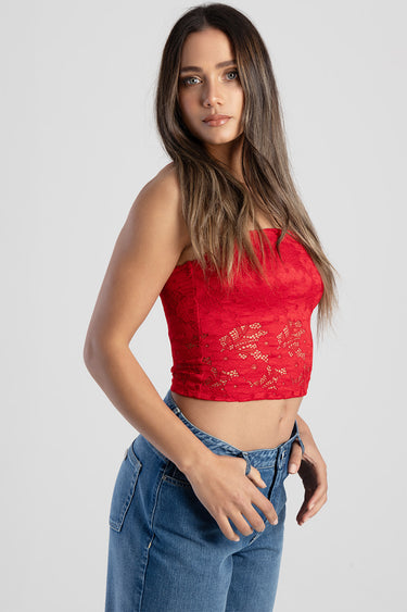 young woman wearing a red lace crop top with a strapless neckline and blue jeans