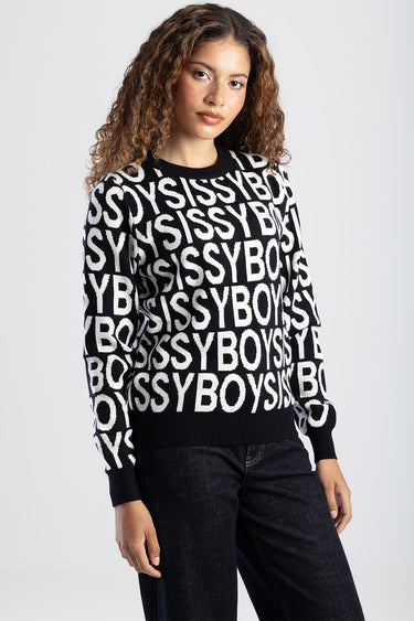 woman wearing a black and white knit sweater with bold all over lettering and ribbed cuffs and hem