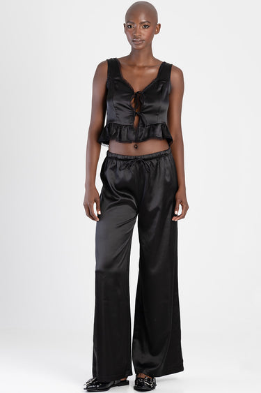 model in black satin crop top with tie front and ruffled hem, and matching wide leg satin pants from Blue Jean Traders