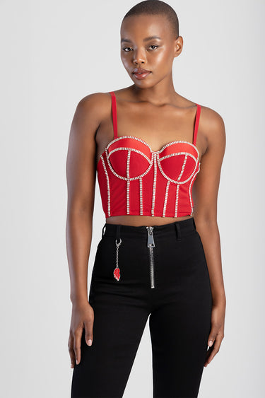 woman wearing a red corset top with pearl trim and structured cups, paired with black high waisted pants and a front silver