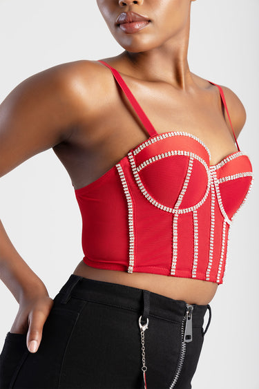 red corset top with rhinestone trim and structured cups on a model, paired with black jeans and metallic zipper detail