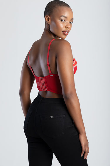woman in a red corset top with a lace-up back and adjustable straps, seen from behind in black jeans