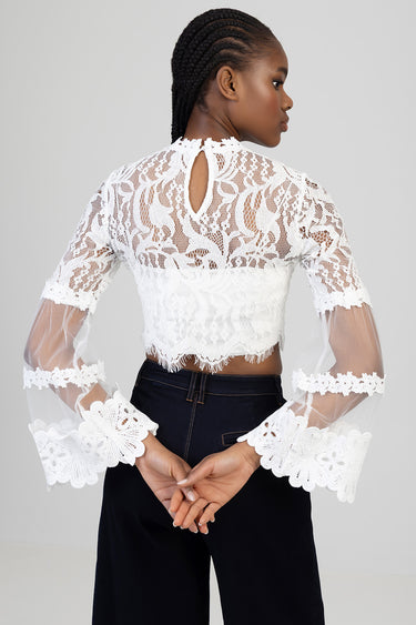 back view of a white lace cropped blouse with sheer long sleeves and a teardrop keyhole at the neck