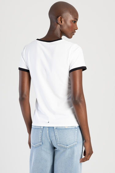 back view of a white short sleeve t shirt with black trim at the neck and cuffs, paired with light blue denim jeans