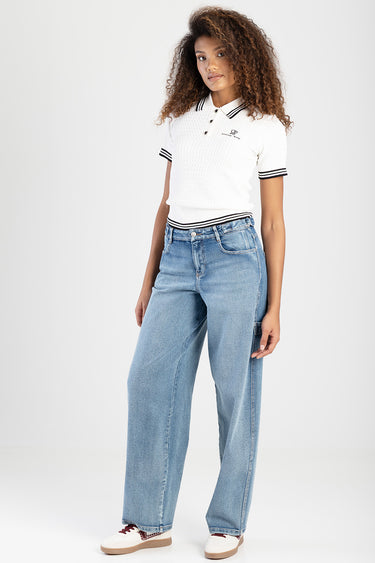 woman in white knit polo with black striped collar and sleeves, high waist light blue wide leg jeans, white sneakers with