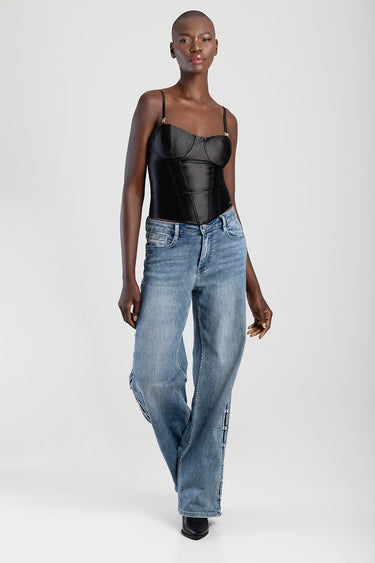 model in black corset top with thin straps paired with light blue wide leg jeans and black boots