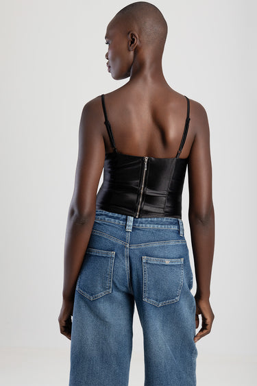 back view of a model wearing a black structured corset top with thin straps and a back zipper, paired with blue jeans