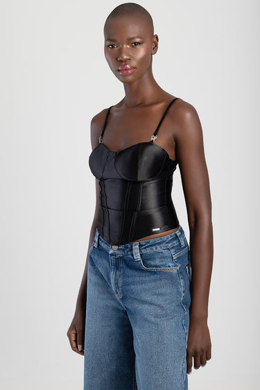 woman in a black satin corset top with thin straps and blue jeans