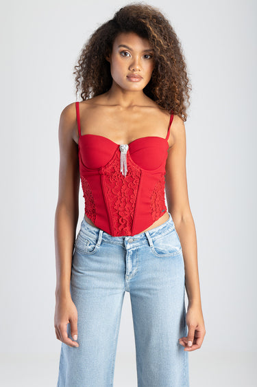 red corset top with lace panels and jeweled pendant, thin straps, shown on a model in light wash jeans
