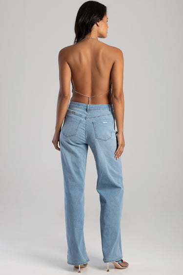 woman from behind wearing light blue jeans and a delicate chain around the back, sandals