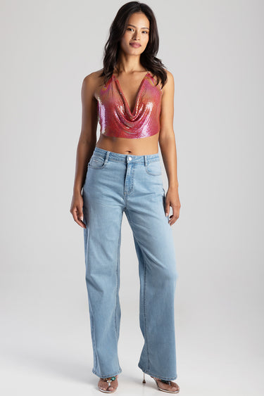 woman in pink sequin draped cropped top and light blue wide leg jeans with sandals