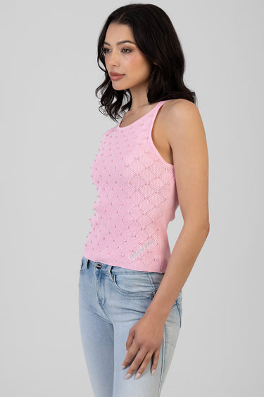 pink sleeveless knit top decorated with pearl beads worn by a woman in light wash jeans