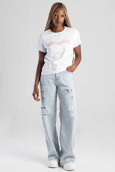 woman in white t shirt with pink script across chest and light blue distressed wide leg jeans with white sneakers