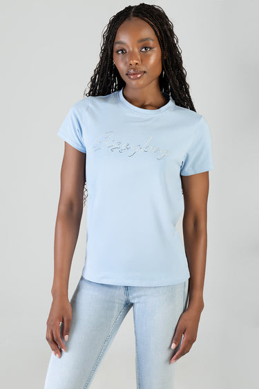 woman wearing a pale blue short sleeve t shirt with rhinestone script across chest