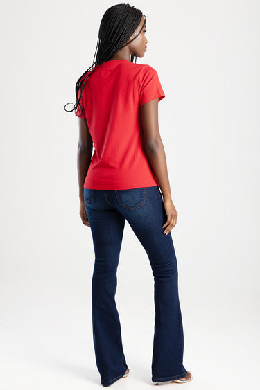 woman wearing a red short sleeve t shirt and dark indigo bootcut jeans, back view