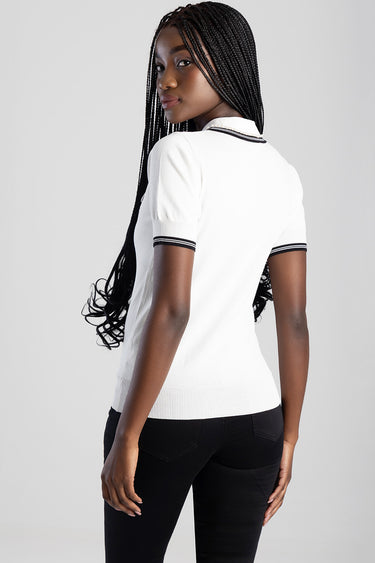 white knit top with black trim on the collar and sleeves, back view