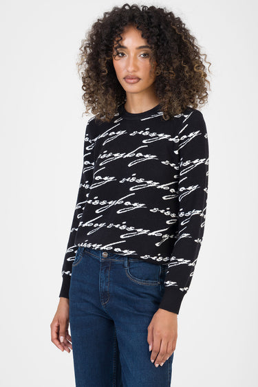 woman in black knitted sweater with white cursive lettering pattern, long sleeves, ribbed cuffs and hem, paired with dark
