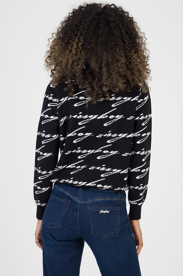 back view of a person wearing a black knit sweater with white cursive script pattern paired with blue jeans