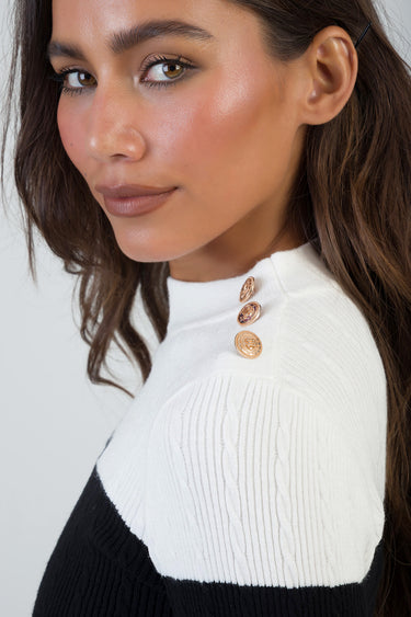 close up of a woman wearing a white ribbed knit top with gold buttons at the shoulder