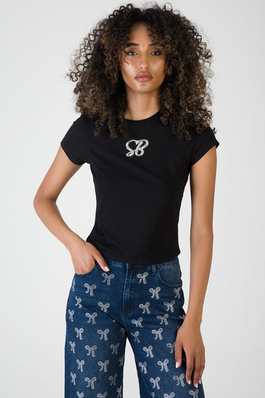black short sleeve crew neck top with a rhinestone logo on the chest, paired with blue jeans featuring white bow patterns