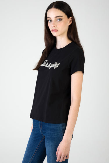 woman wearing a black short sleeve t-shirt with silver sequin script across the chest
