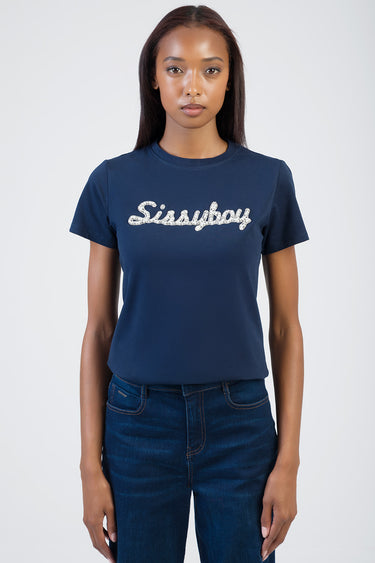 woman wearing a navy blue short sleeve t shirt with white script logo across the chest, standing against a light background