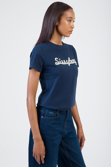 model wearing navy blue short sleeve t shirt with silver rhinestone script logo on chest, paired with dark denim jeans