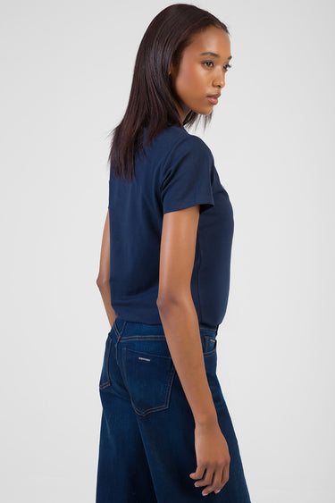 woman wearing a navy short sleeve t shirt and dark blue jeans side profile