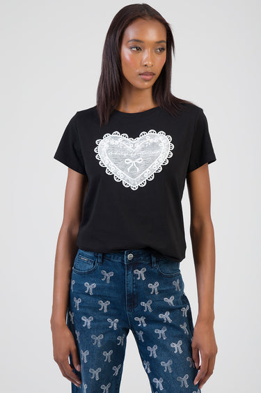 woman wearing black short sleeve t shirt with a large white lace heart on the front, paired with blue jeans featuring white