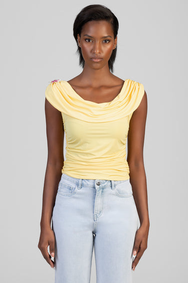 woman wearing a pale yellow draped neckline top with ruched sides and light wash jeans