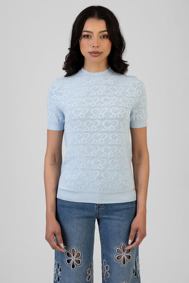 woman wearing a light blue knit top with short sleeves and lace pattern.
