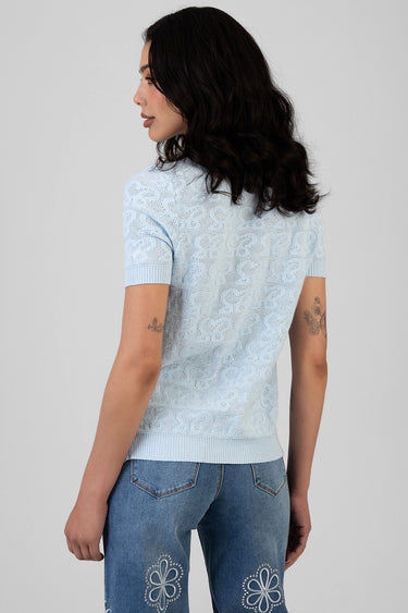 woman seen from behind in a light blue lace knit top with short sleeves and ribbed hem, paired with faded blue jeans