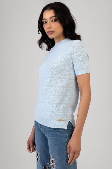 woman wearing a light blue short sleeve knit top with floral lace pattern and ribbed hem