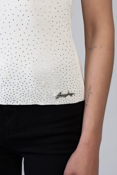 white knit top dotted with small pearls and tiny stones, logo plaque at hem, worn by model with tattooed arm