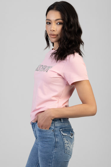 woman wearing a pink short sleeve crew neck t shirt with a glittery logo across the chest