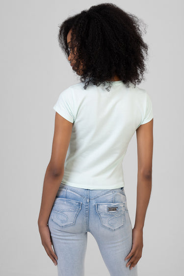 woman with curly hair wearing a pastel mint short sleeve t shirt and light wash jeans back view
