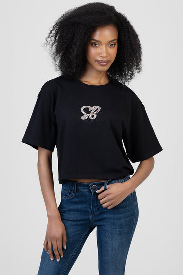 woman in black short sleeve t shirt with a rhinestone logo on the chest, paired with blue jeans