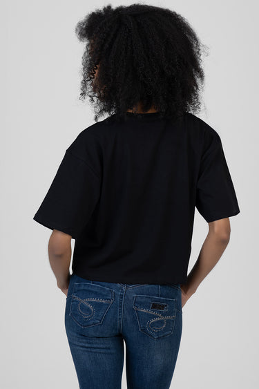 back view of a person wearing a black boxy short sleeve t shirt and blue jeans