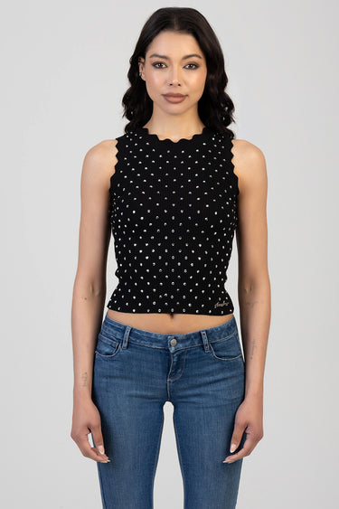 woman wearing a black sleeveless knit top with white polka dots and scalloped neckline, cropped, with blue jeans
