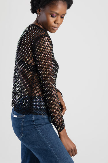 woman wearing a black mesh long sleeve top with rhinestones, from blue jean traders, paired with blue jeans, side view