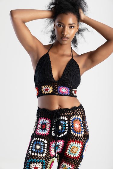 woman wearing a black crochet halter top and a matching crochet skirt with multicolor granny squares