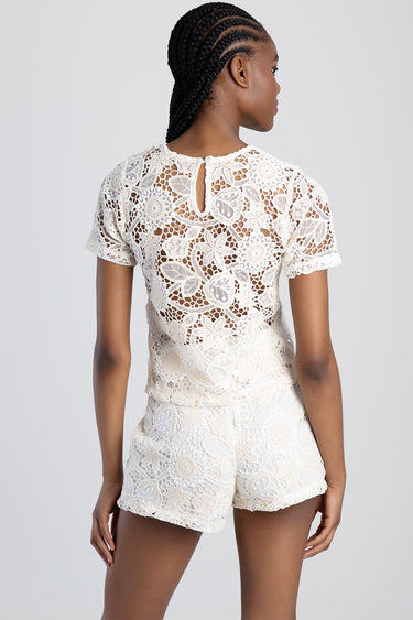 back view of a model wearing a cream floral lace short sleeve top and matching shorts