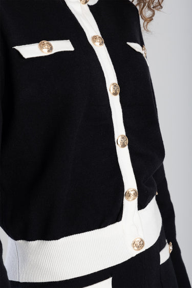 black knit cardigan with white trim along the placket and hem and gold buttons along the front