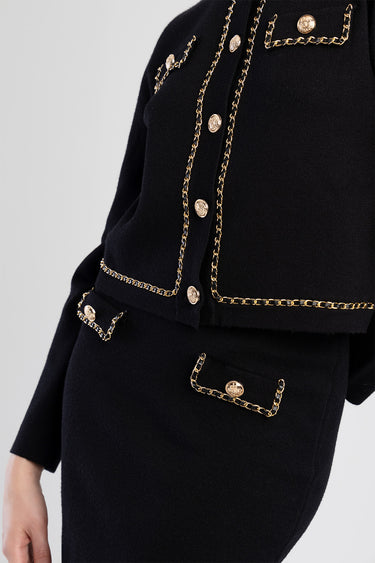 black knit cardigan with gold chain trim along edges and pockets with gold buttons