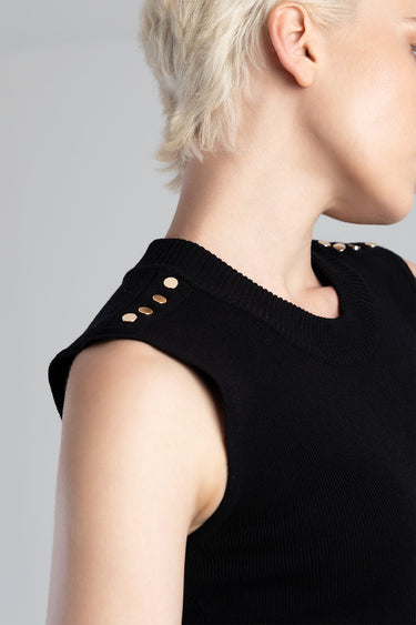 side profile of a person wearing a black knit sleeveless top with gold shoulder studs