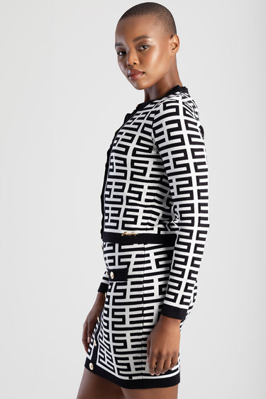 woman wearing a black and white geometric knit cardigan with matching skirt and gold buttons