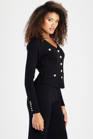 woman wearing a navy knit cardigan with gold buttons and ribbed texture, side view